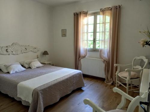 une chambre avec un lit et deux chaises et une fenêtre dans l'établissement Maison de Charme avec piscine dans le Parc Naturel des Alpilles, à Saint-Rémy-de-Provence