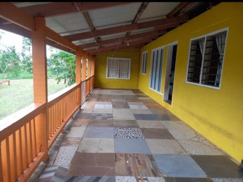 an empty porch of a house with a yellow wall at JayDees Home Retreats Homestay in Naselesele
