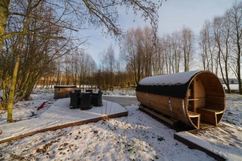 a wooden hobbit house in a snow covered field at Barabois luxury vacation home in Ronse