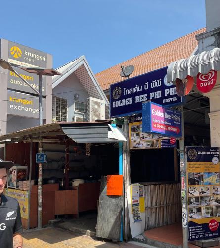 a man standing in front of a store with signs at Golden Bee PhiPhi in Phi Phi Don