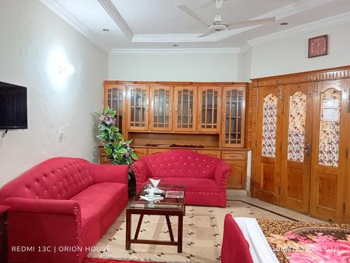 Una sala de estar con dos sofás rojos y una mesa. en Orion International Guest House, en Islamabad