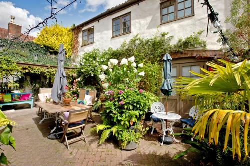 a patio with a table and chairs and flowers at Woodville Barn in Dunster