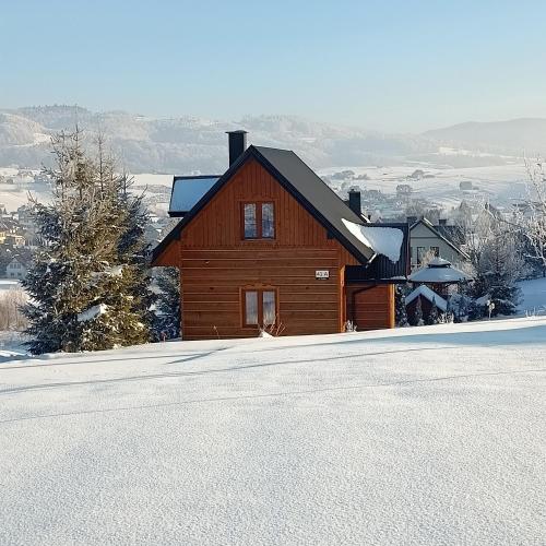 a wooden house in the snow in front of a road at Domek u Stolarza in Grywałd