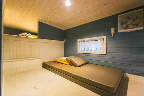 a small room with a bed and a window at PICA Fujiyoshida in Fujiyoshida