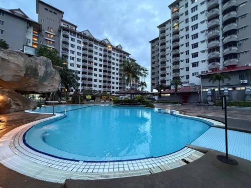 a large blue swimming pool with buildings in the background at Anneliese suite Glory Beach Resort in Port Dickson