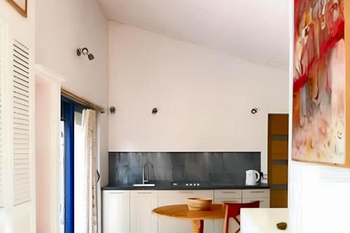 une cuisine avec des armoires blanches et une table dans l'établissement Appartement charmant à Saint-Quentin-la-Poterie, 40 m², jardin., à Saint-Quentin-la-Poterie