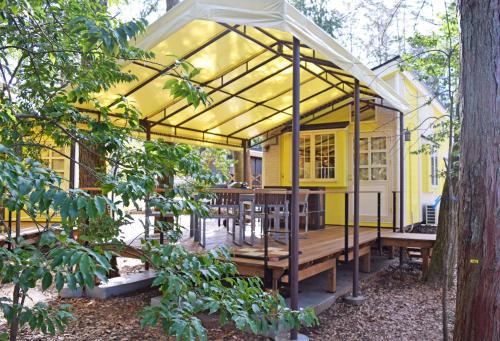 a yellow house with a wooden table and benches at PICA Fujiyoshida in Fujiyoshida