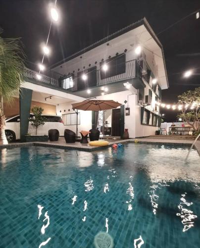 a swimming pool with an umbrella in front of a house at 夜色V8s in Kampong Alor Gajah