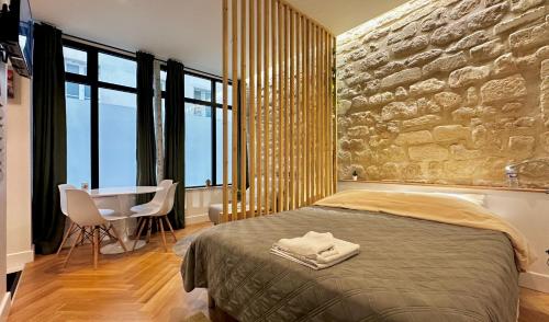 - une chambre avec un mur en pierre, un lit et une table dans l'établissement Studio Amelot, Charming & Pierre, à Paris