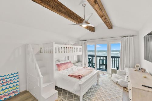 a white bedroom with a bunk bed and a balcony at Oceanfront Escape A Coastal 3Br-2Ba Retreat With Stunning Views in New Smyrna Beach