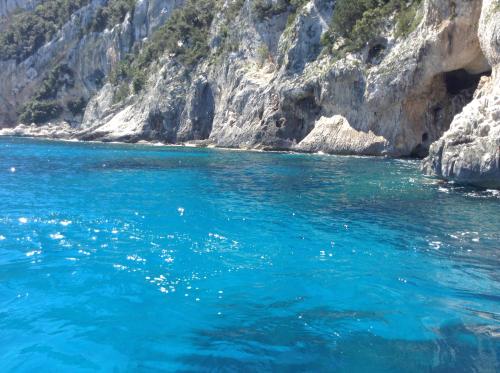 a body of water next to a rocky cliff at B&B Luce Viola in Dorgali