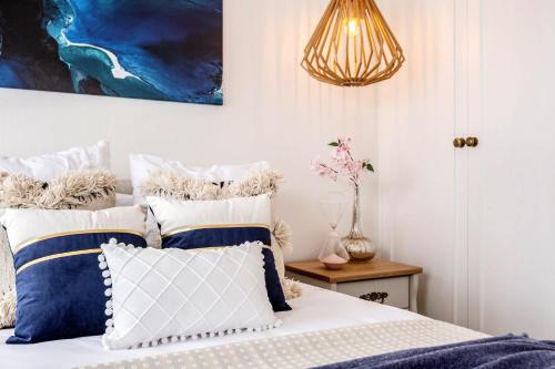 a bedroom with a bed with blue and white pillows at VAQUAY The Hamptons In Williamstown in Williamstown