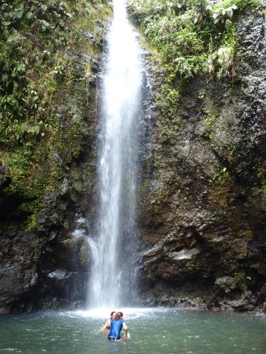 a person in the water in front of a waterfall at La Maison Du Voyage in Tevaitoa