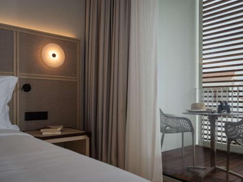 a hotel room with a bed and a desk and a window at Mercure Ponta Delgada Azores in Ponta Delgada