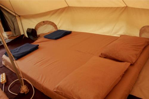 a bed in a tent with two pillows on it at Lembah Pinus Cikole in Tangkubanperahu
