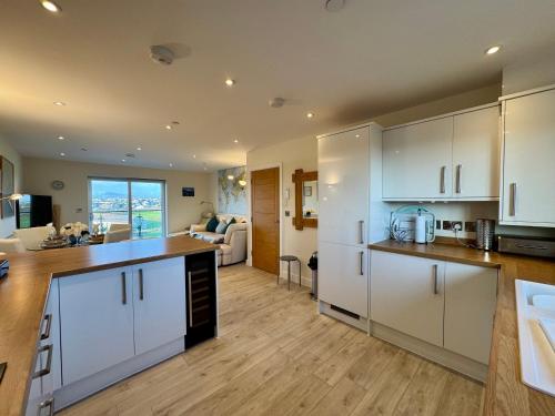 a kitchen with white cabinets and a living room at Gwel Y Bae-2 Bed-en-suite-Lift-Pet friendly in Trearddur