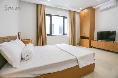 a bedroom with a large white bed with a flat screen tv at Moonstone Homestay & Cafe - Vinhomes Ocean Park 2 in Hòa Bình