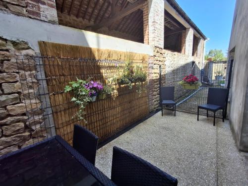 - une terrasse avec 2 chaises et des fleurs sur un mur dans l'établissement Auxpetitsloups, à Issancourt-et-Rumel