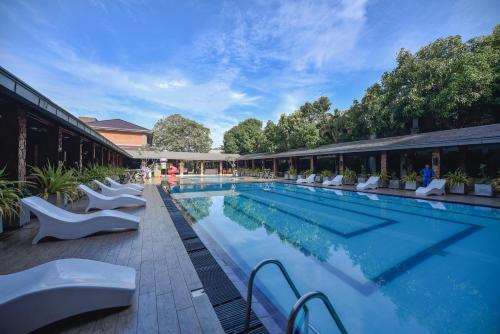 a large swimming pool with white chairs next to a building at The Full Moon Hotel Katunayake in Katunayake