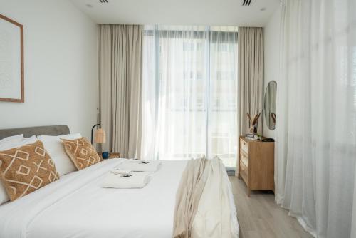 a bedroom with a large white bed and a window at Comfy 1BR w Cinema Room Business Centre Pool Table and Sauna in Dubai