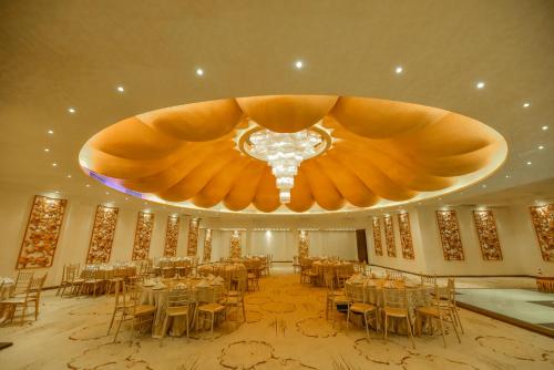 a banquet hall with tables and a large chandelier at The Full Moon Hotel Katunayake in Katunayake