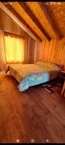 a bedroom with a bed in a wooden room at Cabaña Belén in Neltume