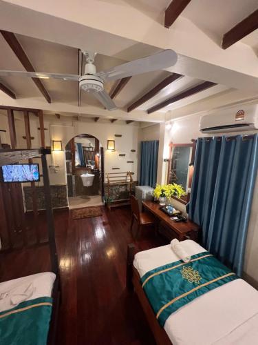 a living room with two beds and a table at Chaluenxay Legend Hotel in Luang Prabang