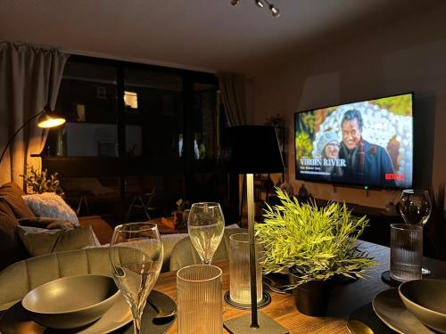 a table with wine glasses and a television in a living room at Spacious and modern flat in Archway in London