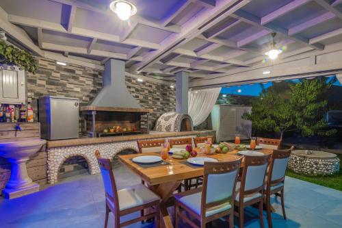 an outdoor kitchen with a table and a fireplace at Villa Shameti - Private Villa with Pool and Billiards Near Zakynthos Town By Villa Mana Gers in Zakynthos Town