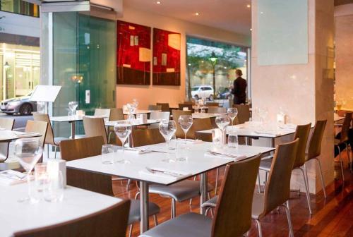 a restaurant with white tables and chairs with wine glasses at CBD Two Bedrooms Apartment in Brisbane