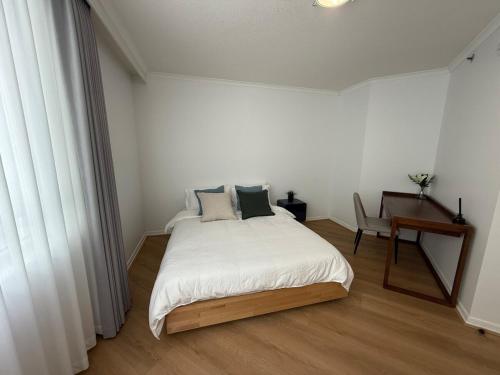 a white bedroom with a bed and a desk at CBD Two Bedrooms Apartment in Brisbane