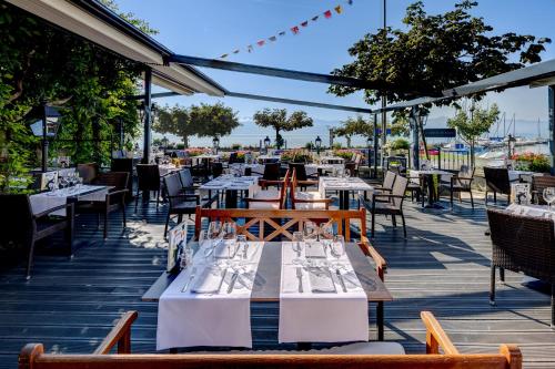 a restaurant with white tables and chairs on a deck at Romantik Hotel Mont Blanc au Lac in Morges