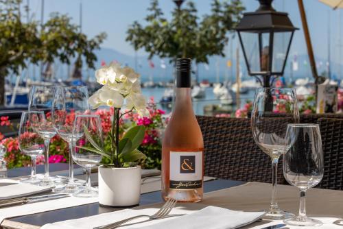 a bottle of wine sitting on a table with glasses at Romantik Hotel Mont Blanc au Lac in Morges