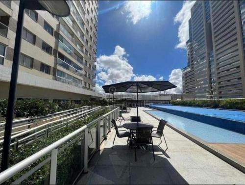 einen Tisch und Stühle mit einem Sonnenschirm neben einem Pool in der Unterkunft Apartamento charmoso e confortável no DF Century Plaza in Brasilia