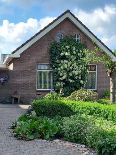 a red brick house with a garden in front of it at B&B Kleintje Eleveld in Eleveld