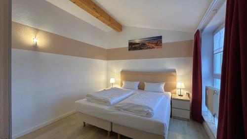 a bedroom with a bed with white sheets and a window at Ferienappartement im Seepark Sellin in Ostseebad Sellin