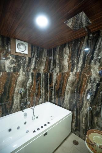 a bathroom with a tub and a stone wall at RAJWADA RESORT & HOTEL in Raipur