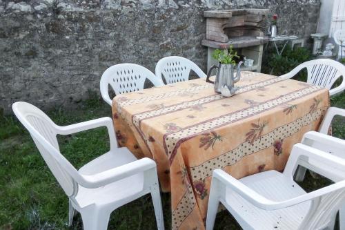 - une table avec des chaises blanches et un vase de fleurs dans l'établissement Maison de charme à Primelin avec jardin et parking privé, à Primelin