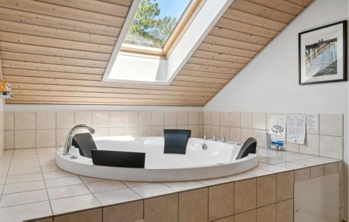 a bath tub in a bathroom with a skylight at Awesome Home In Rødby With Sauna in Rødby