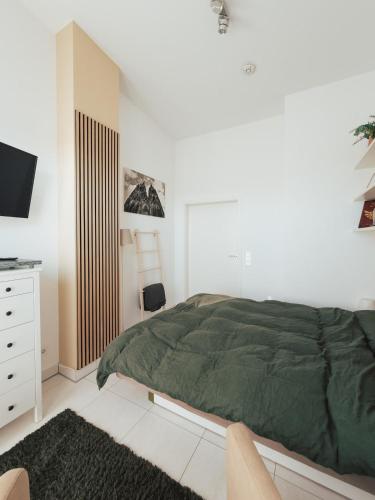a white bedroom with a green bed and a tv at Nahe Messe - Privates Gästezimmer mit Bad in einer Wohnung in Cologne