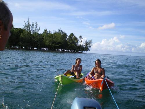 two children are sitting on kayaks in the water at La Maison Du Voyage in Tevaitoa