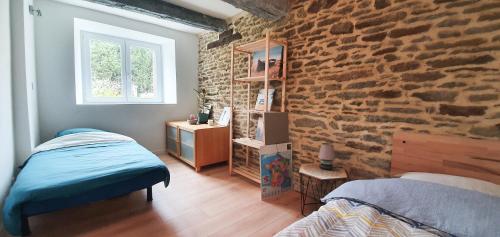 une chambre avec un lit et un mur de briques dans l'établissement Belle maison familiale dans la campagne Bretonne, à La Croix-Helléan