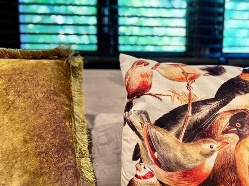 two pillows with birds on them sitting on a couch at LA CHENEAUDIÈRE - Hôtel Spa - Relais & Châteaux - Restaurant étoilé in Colroy-la-Roche