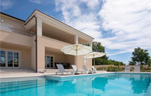 a swimming pool with chairs and umbrellas next to a house at Villa Stella Smoljanci in Smoljanci