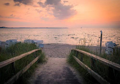 a path leading to a beach with a sunset on the water at Strandliebe in Scharbeutz, stilvolle Ferienwohnung, 150m zum Strand! Sonnenbalkon, ruhig gelegen, kostenfreier Parkplatz, Fahrstuhl in Scharbeutz