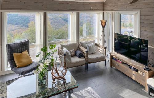 a living room with a flat screen tv and windows at 3 Bedroom Awesome Home In Nordfjordeid in Nordfjordeid