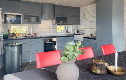 a kitchen with red chairs and a vase with a plant at 3 Bedroom Awesome Home In Nordfjordeid in Nordfjordeid
