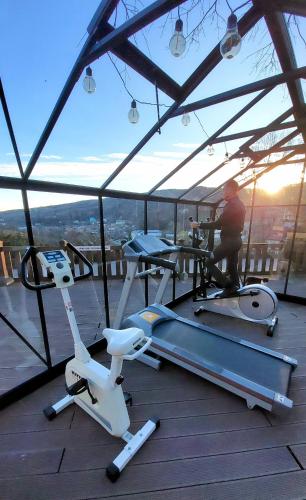 a man on a treadmill and an exercise bike on a deck at Pension Casa cu Tei in Sărata-Monteoru
