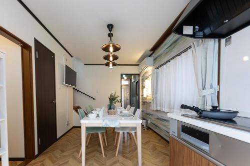 a kitchen and dining room with a white table and chairs at OB 関西空港 大阪梅田 心斎橋直通 京セラドーム1分 usj10分 静かな住宅街 専用駐車場付き in Osaka