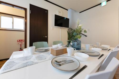 a white table with plates and silverware on it at OB 関西空港 大阪梅田 心斎橋直通 京セラドーム1分 usj10分 静かな住宅街 専用駐車場付き in Osaka